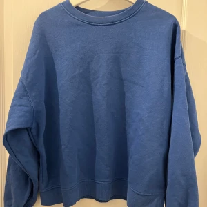 Blå sweatshirt från Lindex - Säljer en blå sweatshirt från Lindex. Tröjan har en klassisk rund halsringning och långa ärmar. Perfekt för en avslappnad stil.