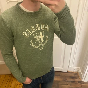 Grön tröja från Morris - Säljer en snygg grön tröja från Morris med tryck framtill. Tröjan har långa ärmar och ribbade muddar vid ärmslut och hals. Perfekt för en stilren look.  Modellen är ca 182, tveka inte att kontakta vid eventuella frågor 😀