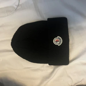 Svart moncler mössa - Svart moncler mössa, EJ ÄKTA! Säljer då den inte riktigt är min stil längre.