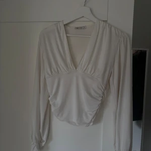 Vit långärmad topp - Vit topp med djup v-ringning och långa ärmar från Nelly. 