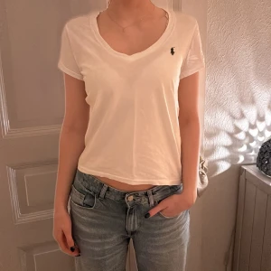 Vit t-shirt från Ralph Lauren - Säljer en klassisk vit t-shirt från Ralph Lauren med en liten broderad logga på bröstet. T-shirten har en v-ringad hals och korta ärmar