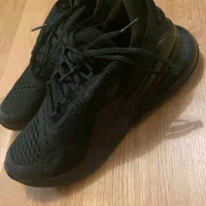 Svarta sneakers från Nike - Säljer ett par svarta Nike sneakers med snörning. Skorna har en modern design med ventilerande material och en bekväm sula. Perfekta för vardagsbruk eller träning.