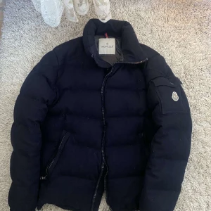 Svart dunjacka från Moncler - Tja! Säljer nu min otroligt snygga montegenevre  jacka från Moncler. Jackan är i top skick och är bara använd ett fåtal gånger, jackan är givetvis äkta. Passar perfekt för det kalla vädret. Storlek M/L. Sitter perfekt för sig som är 180-187. Frågor eller funderingar?🙌