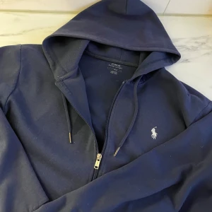 Mörkblå hoodie från Ralph Lauren - Säljer en mörk blå Polo kofta, storlek L, riktigt fin och inga defekter, vid frågor hör av er !