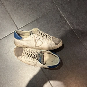 Vita sneakers med blå detaljer - Snygga vita sneakers med blå detaljer och snörning. Skorna har en klassisk design med en grå tå och är perfekta för en avslappnad stil. Pris kan diskuteras 