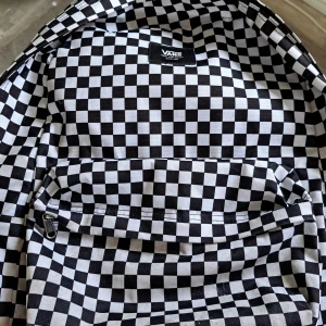 Svartvit rutig ryggsäck från Vans - Säljer en cool svartvit rutig ryggsäck från Vans. Den har ett klassiskt schackrutigt mönster och en praktisk dragkedja framtill. Perfekt för att bära dina grejer med stil. Ryggsäcken har också en innerficka för extra förvaring. Ett stort fack och ett litet fack. Den har lite skada på under sidan av väskan men det syns knappt. Jag skulle säga 7/10 skick jag har haft den i typ 2 år. Ny pris 300kr jag säljer den för 100kr 