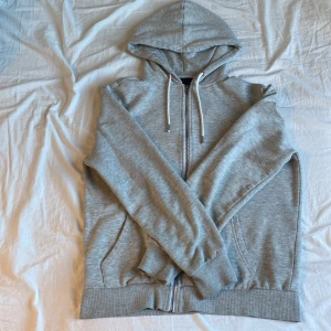 Grå hoodie från Lager 157 - Säljer en grå hoodie från Lager 157 i storlek M. Den har en dragkedja framtill och en mysig huva med snören. Perfekt för kyliga dagar med sin mjuka insida.