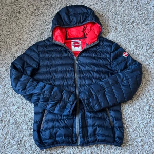 Mörkblå pufferjacka från Colmar - Säljer en snygg mörkblå pufferjacka från Colmar med en kontrasterande röd insida. 