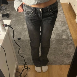Lågmidjade bootcutjeans - Säljer ett par grå lågmidjade bootcut jeans med detaljer på bakfickorna. Storlek 24 Mini defekt (sista bild) då jag satt skosnöre i midjan