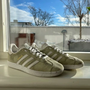Adidas Gazelle i beige mocka - Snygga Adidas Gazelle sneakers i beige mocka med vita detaljer och snörning. Helt ok skick, 6/10 men annars ett par feta skor☀️