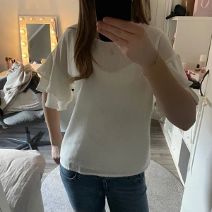 Vit blus med volangärmar - Säljer en vit blus med volangärmar. Blusen har en rund halsringning och är tillverkad i ett lätt och luftigt material. 