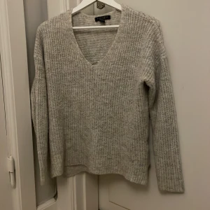 V-ringad stickad tröja  - Mysig ljus grå stickad tröja från Amisu med v-ringning. Lite slit längst ner på båda sidorna🩷