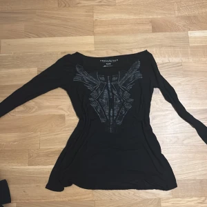 Svart långärmad topp från Aéropostale - Säljer en svart långärmad topp från Aéropostale med ett unikt mönster framtill. Toppen har en öppen rygg som ger en snygg detalj. Perfekt för att lägga till en stilfull touch till din garderob.