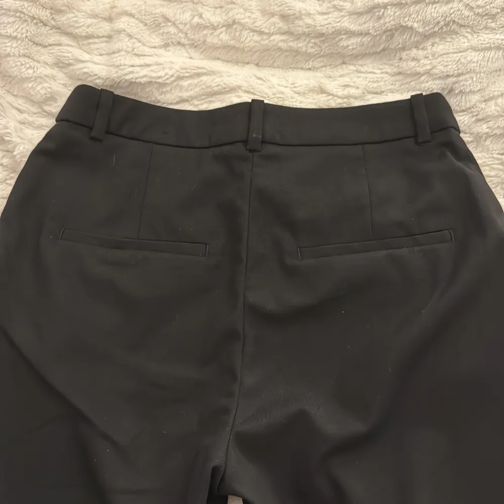 Snygga svarta kostymbyxor från H&M i en klassisk design. Byxorna har en rak passform med diskreta fickor bak och hällor för bälte. Perfekta för en stilren look. 🌺💗. Farkut & Housut.