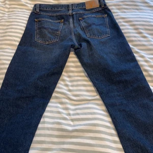 Blå jeans från Nudie Jeans - Säljer ett par klassiska blå straight  jeans från Nudie Jeans. Skulle säga att dem sitter lite slimmat. Perfekta för en avslappnad stil med fem fickor och knappgylf. Storlek W30 L32. Modellen är 184cm