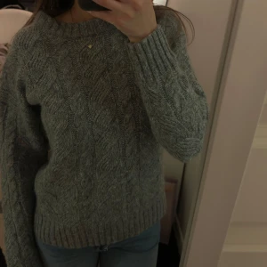 Grå stickad tröja - Säljer en super mysig grå stickad tröja med kabelstickat mönster. Använd endast en gång!☺️