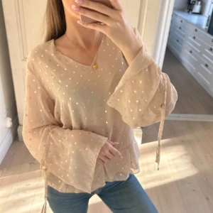 Beige blus med volangdetaljer - Säljer en söt beige blus från Kappahl med prickigt mönster och volangdetaljer vid nederkanten