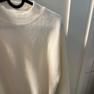 Vit ull tröja - Säljer en stilren vit stickad tröja med ribbad krage. Perfekt för kyligare dagar och ger en klassisk look. Tröjan har långa ärmar och är supermjuk att ha på sig. Kommer inte ihåg vad det är för märke och har därmed sänkt priset!