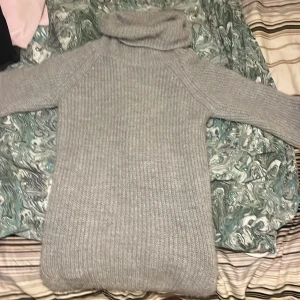 Grå stickad polotröja - Mysig grå stickad polotröja perfekt för kyliga dagar. Tröjan har en hög polokrage och långa ärmar, vilket gör den extra varm och bekväm. Den ribbade strukturen ger en klassisk look. Väldigt bra stickad gjord i Italien 