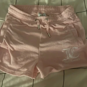 Rosa shorts från Juicy Couture - Säljer ett par mjuka och bekväma rosa shorts från Juicy Couture. De har en elastisk midja med snörning och ett broderat JC-märke på framsidan. Perfekta för en avslappnad stil. vi kan självklart diskutera priset bara att säga till!
