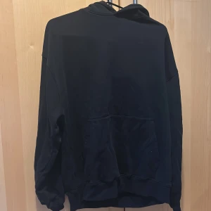 Svart hoodie från colourful standards - Säljer en klassisk svart hoodie med känguruficka framtill. Perfekt för en avslappnad stil och passar till det mesta. Hör av dig vid intresse!