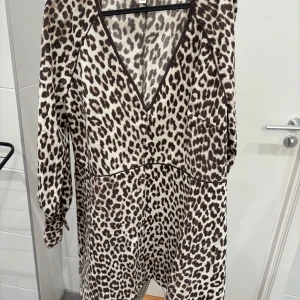 Leopardmönstrad klänning med v-ringning - Snygg leopardmönstrad klänning med v-ringning och långa ärmar. Perfekt för att sticka ut med ett djärvt mönster. Klänningen har en bekväm passform och är lätt att styla för olika tillfällen.köpt för en månad sen och använd en gång dessvärre för stor 