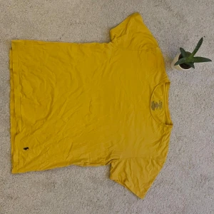 Gul t-shirt från Ralph Lauren - Snygg gul t-shirt från Ralph Lauren med klassisk logga broderad i svart på framsidan. Perfekt för en avslappnad stil. Tillverkad i mjuk bomull för extra komfort.
