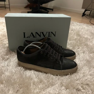 Lanvin - Säljer nu dessa sjukt snygga lanvin skorna i färgen grå. Skorna är i mycket fint skick och allt og du ser på sista bilden medföljer. Skorna är i storlek 43 men sitter en aning större. Skorna är köpta ifrån farfetch. Om du vill ha ett par stilrena och bekväma sneakers så är detta det perfekta valet för dig!