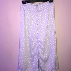 Ljusblå blommig kjol med knappar - Charmig ljusblå kjol med vita blommor och knappar framtill. Kjolen har en slits som ger extra rörelsefrihet och en elastisk midja för bekväm passform. Perfekt och super gulligt till en somrig look! 