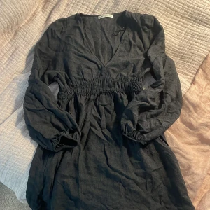 Svart/grå klänning från Pull&Bear - Snygg svart klänning från Pull&Bear med v-ringning och 3/4 ärmar. Den har en elastisk midja. Endast använd ett fåtal gånger