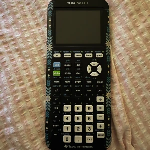 TI-84 Plus CE-T Grafräknare - Säljer en TI-84 Plus CE-T grafräknare från Texas Instruments. Den har en unik design med blommönster runt skärmen och knapparna. Perfekt för avancerade matematiska beräkningar och grafritning. Kommer med ett skyddande bakstycke och laddaren.