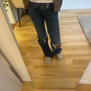 Blå jeans med slitningar - Skitsnygga lågmidjade boot cut jeans med hål.Aldrig använda, ändast provade.Midjemått rakt över 32,innerbenslängd 83 cm💕Kom med prisförslag!