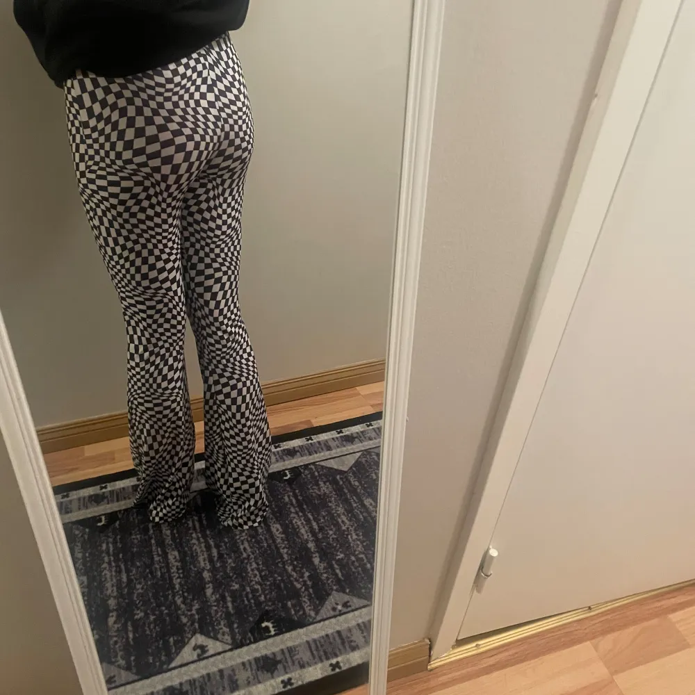 Snygga svartvita byxor med ett iögonfallande rutigt mönster. Byxorna har en tight passform och är bootcut-stil, vilket ger en trendig look. Perfekta för att sticka ut i mängden!. Farkut & Housut.