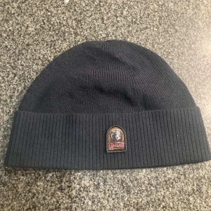 Mörk blå mössa från Parajumper - Snygg svart mössa från Parajumpers med ribbad kant och broderad logotyp framtill. Perfekt för att hålla värmen under kyliga dagar. Lägg gärna prisförslag. Kan tyvärr inte frakta via PostNord 