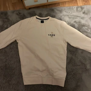 Vit tröja från Vans med ormmotiv - Säljer en vit tröja från Vans med ett coolt ormmotiv och blommor på ryggen. Tröjan har långa ärmar och en klassisk passform. 🐍🌼.        