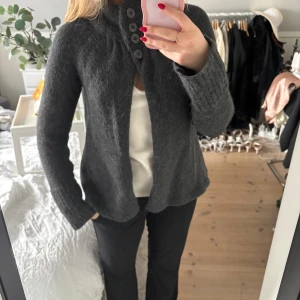 Mörkgrå kofta med polokrage  - Mörkgrå kofta i alpackaull med hög krage med knappar på. Aldrig använd😊