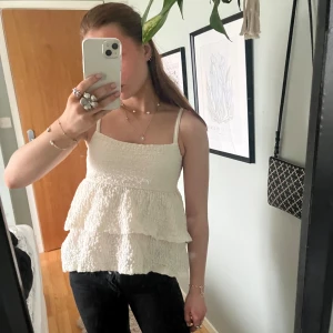 Vit volangtopp från GinaTricot - Säljer denna söta vit/beiga volangtopp från GinaTricot. Den är använd ett fåtal gånger så den är så gott som ny!🫶🏻