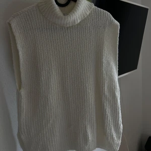 Vit stickad väst från Zara - Säljer en supermysig vit stickad väst från Zara. Perfekt för lager-på-lager under höst och vinter. Den har en hög krage som håller dig varm och är i ett mjukt material som känns skönt mot huden. Passar både till vardags och lite finare tillfällen.