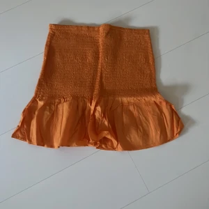 Orange kjol  - En orange kjol med volanger nertill 