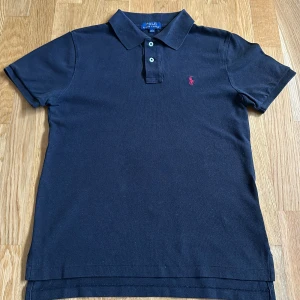 Svart pikétröja från Ralph Lauren - Original pris på hemsidan: 1495 kr ‼️‼️SVART ‼️‼️  pikétröja från Ralph Lauren. Den har en liten röd loggaoch är gjord i mjuk bomull. Bra kvalite. Skriv till mig för bättre bilder 