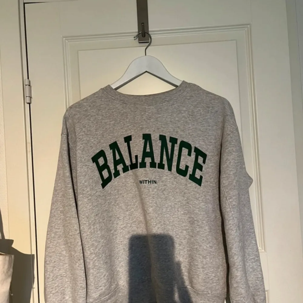 Säljer en grå sweatshirt med texten 'BALANCE WITHIN' i mörkgrön färg på framsidan. Tröjan är långärmad och perfekt för en avslappnad stil. Den är i bra skick och passar till både vardag och mysiga hemmakvällar.. Tröjor & Koftor.