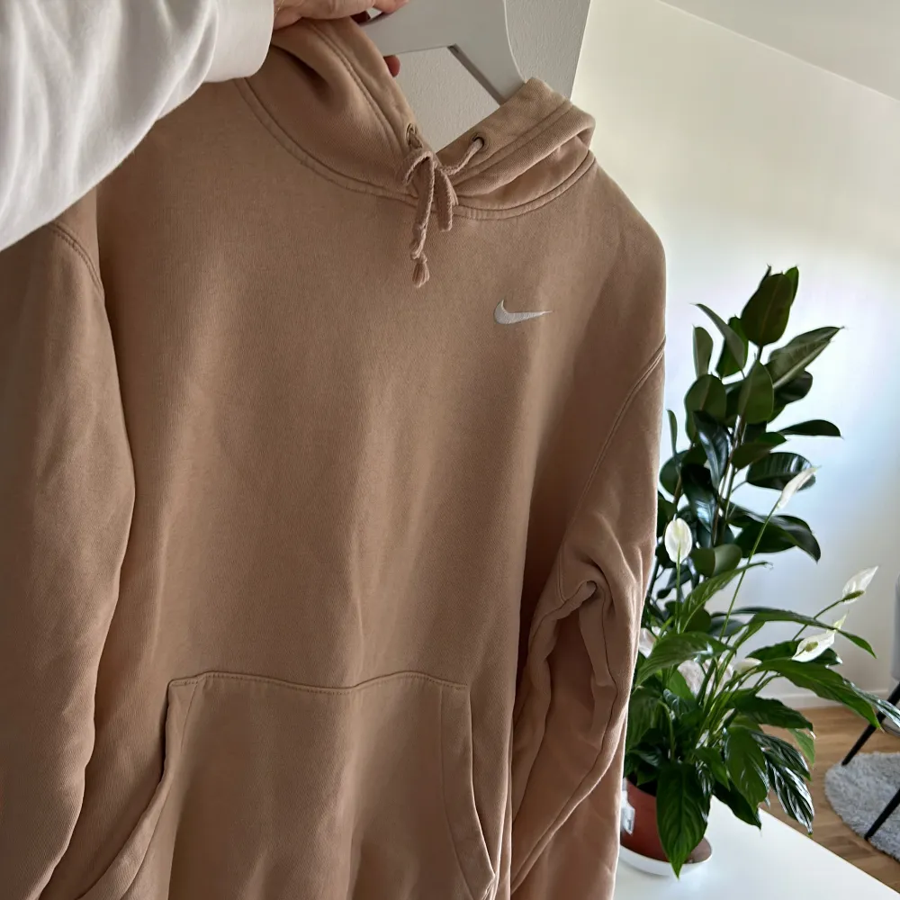 En rosa/beige hoodie från Nike som är i storlek S dock är passformen oversized.. Hoodies.