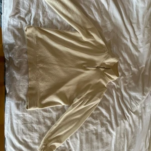 Beige fleece tröja med dragkedja - Säljer en mysig beige fleece tröja med halv dragkedja. Perfekt för kyliga dagar med sin mjuka och varma känsla. Tröjan har långa ärmar och en hög krage för extra värme. Passar bra till både vardag och speciella dagar.