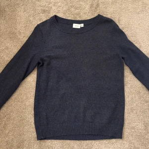 Mörkblå tröja från Vila - Säljer en stilren mörkblå tröja från Vila. Tröjan är långärmad och har en rund halsringning med ribbade kanter vid ärmslut och nederkant. 
