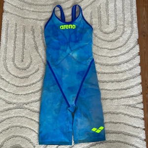 Tie dye blå  tävlingsbaddräkt från Arena carbon glide - Säljer en blå tävlingsbaddräkt från Arena med neongula detaljer. Den har en tight passform och är perfekt för simtävling. Materialet är av hög kvalitet och designen är både funktionell och stilren. Nypris 4000kr säljs för 3000. Använd på 1 lopp.