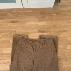 Bruna manchesterbyxor - Säljer ett par jättesöta lågmidjade bruna flared manchesterbyxor med fickor fram och bak. Byxorna har en klassisk design med knappdetaljer och bälteshällor. Står att dom är i XL men tycker dom passar L också. Skriv vid intresse!🌸