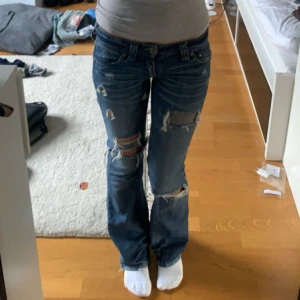 Affliction jeans - Skit snygga lågmidjade bootcut jeans från Affliction. Får knappt på mig dom längre säljer därför. Längst ner på baksidan byxbenet är de ganska slitet men syns inte så mycket när man har på sig dom(se bild). Midjemått: 35,5 cm innerben: 80