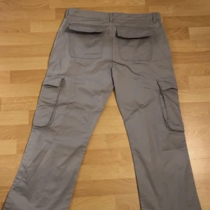 Grå cargobyxor - Säljer ett par grå cargobyxor med flera praktiska fickor. Byxorna har en loose passform och är perfekta för en avslappnad stil. De har en klassisk design med fickor på sidorna och baktill. Aldrig använts. 