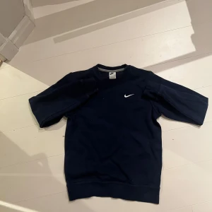 Mörkblå sweatshirt från Nike - Säljer en stilren mörkblå sweatshirt från Nike med det klassiska vita swoosh-loggan broderad på bröstet. Tröjan har en enkel design med långa ärmar och rund halsringning. Perfekt för en avslappnad look. XS( passar 160-172)