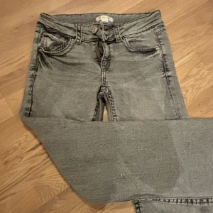 Grå jeans från Gina Tricot - Snygga grå jeans från Gina Tricot i storlek 158. De har en klassisk femficksdesign och en dragkedja framtill. Perfekta för en avslappnad stil.